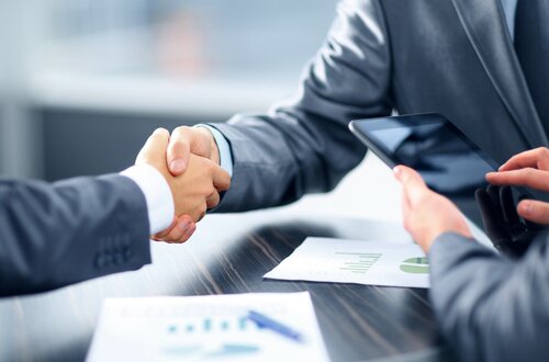 Two people shaking hands over an invoice | Debt collection agency Michigan
